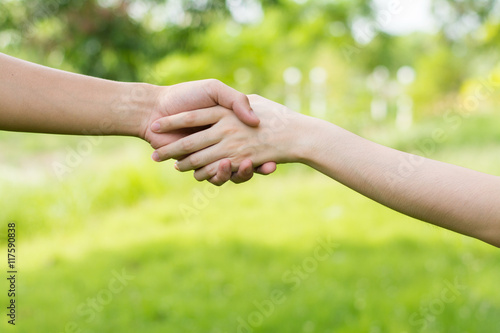 Close up on a man and a woman holding hands at green background,Hand help and hope concept,helping hand © sek_gt