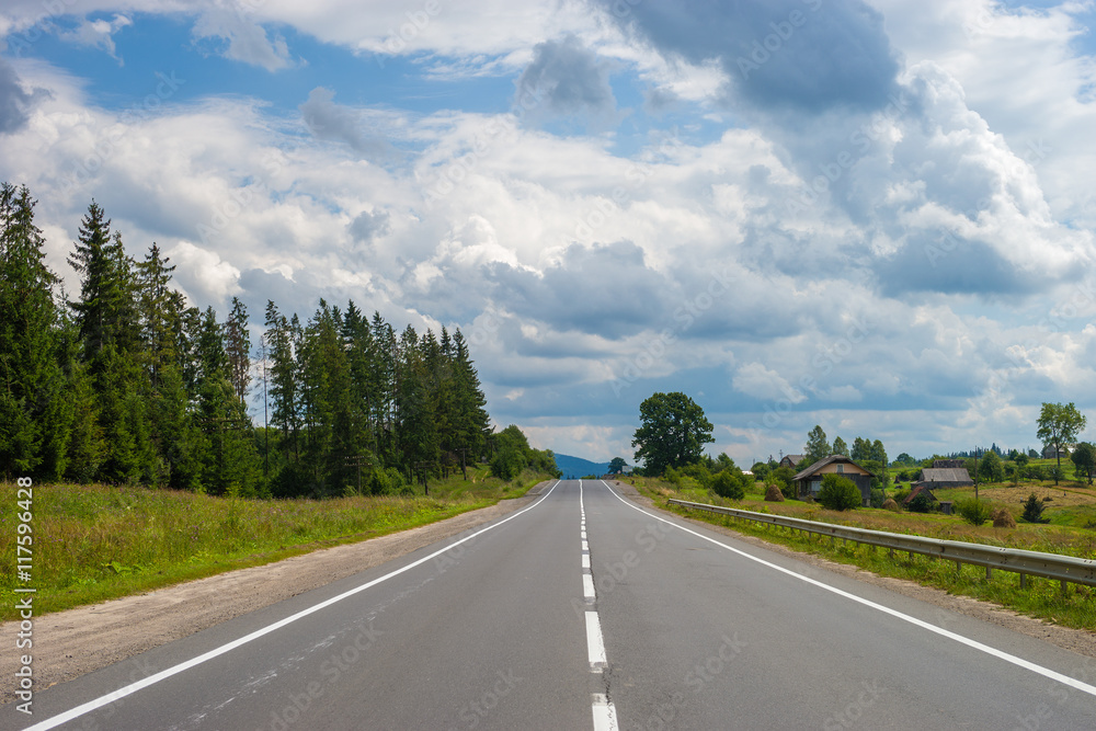 Summer day landscape with road, cloudy sky and small houses. Ukraine, Carpathian. Summer day landscape with road, cloudy sky and small houses. Ukraine, Carpathian.