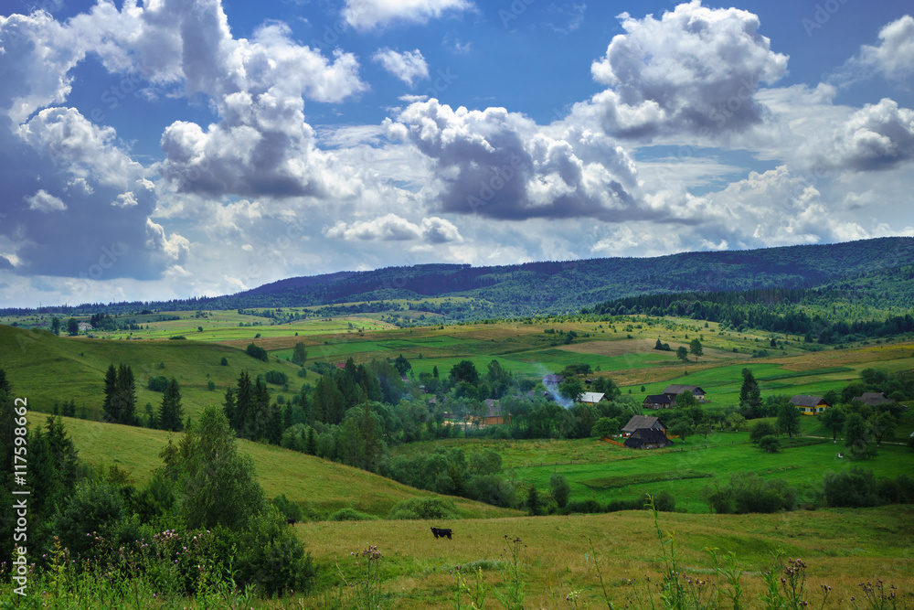 Summer day landscape with cloudy sky, mountains, small houses. Carpathian Mountains. Ukraine. Europe.