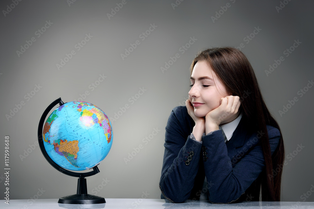 Girl sitting and looking at the globe. Isolated on grey backgrou Girl sitting and looking at the globe. Isolated on grey backgrou