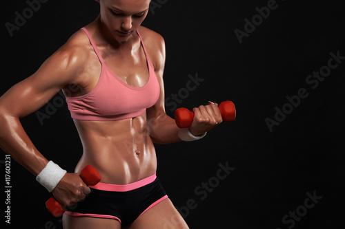 fitness athletic woman pumping up muscles with dumbbells.beautiful blond girl in gym © eugenepartyzan