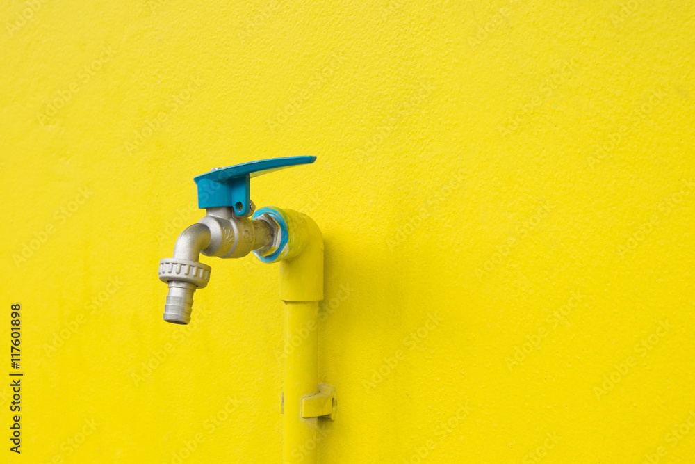 Closeup faucet on concrete Yellow wall background. Water leaking Closeup faucet on concrete Yellow wall background. Water leaking