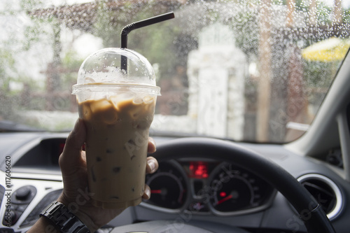 transportation and vehicle concept - hand of man holding a take away cup of iced coffee while parking the car with water drop of raining,boost the energy to drive