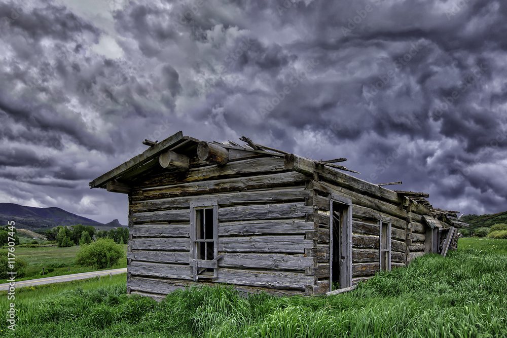 Old abandon log home outside of Yampa Colorado with a building storm in the sky. Old abandon log home outside of Yampa Colorado with a building storm in the sky.