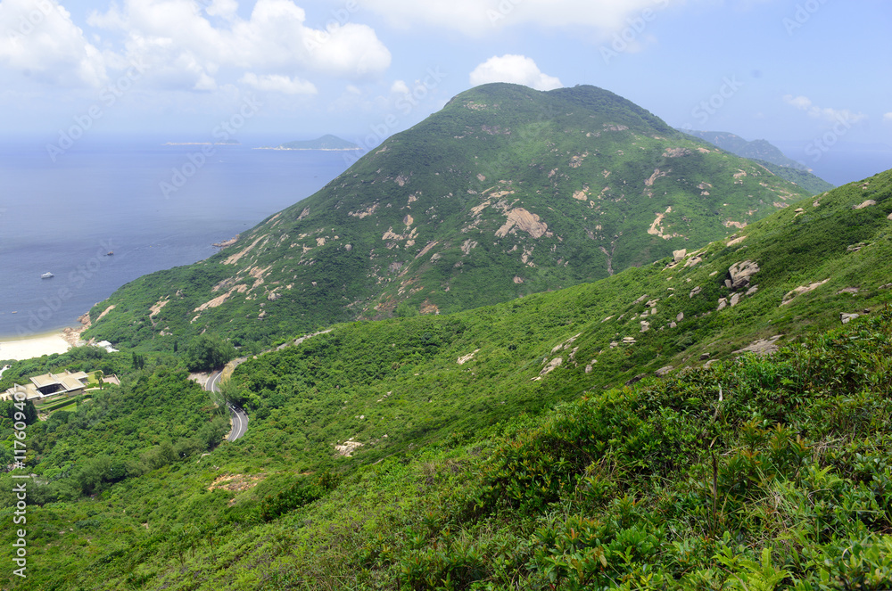 Green Tropical mountains and hiking route on the Dragon's Back trail near Hong Kong with clouds