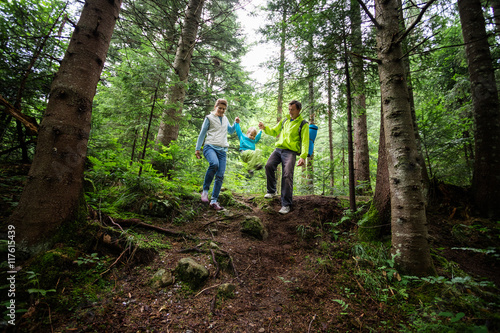 Family of three on a hike in a mountainous forest. Motion blur, the boy walking in the air while holding his parents' hands.