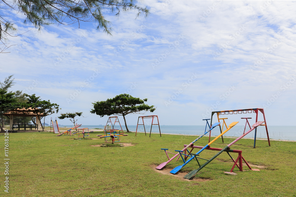 Colorful playground on yard in the park near the beach with clouds and sky background Colorful playground on yard in the park near the beach with clouds and sky background