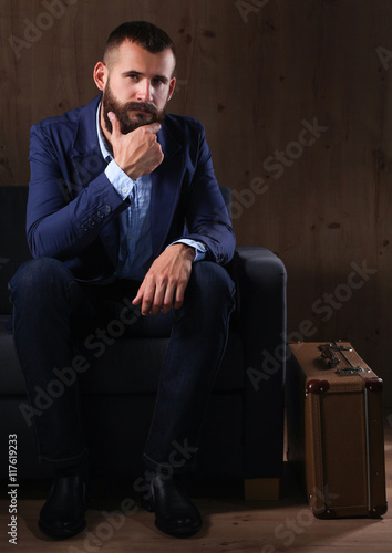 Businessman sitting the sofa in office lobby, isolated on dark background