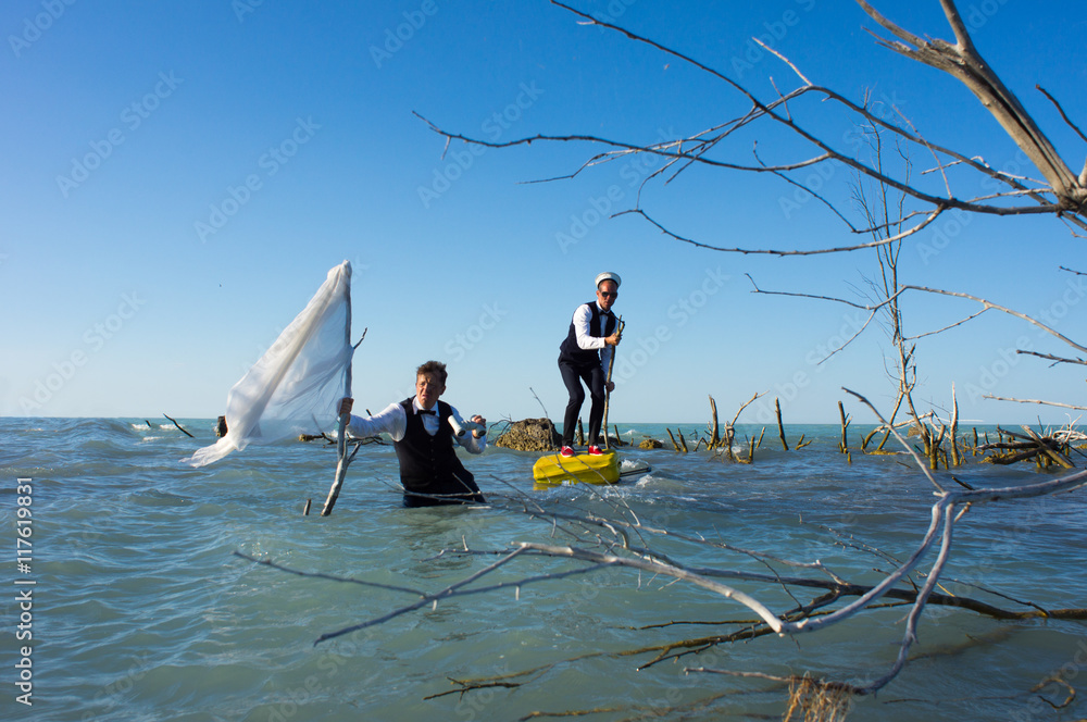 Naklejka premium Two businessmen with a yellow suitcase and white flag, in an extreme journey through the ocean.