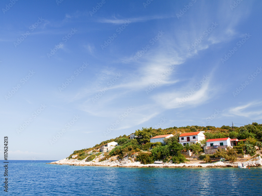 Seascape with beautiful island and with cozy homes, blue sky and