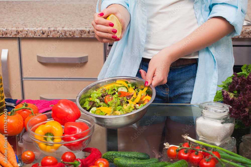 The girl's hands squeezed the lemon into the salad The girl's hands squeezed the lemon into the salad