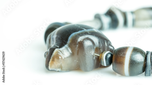 Close up ancient rare carved turtle agate bead separated with variety agate beads on necklace isolated on white background 