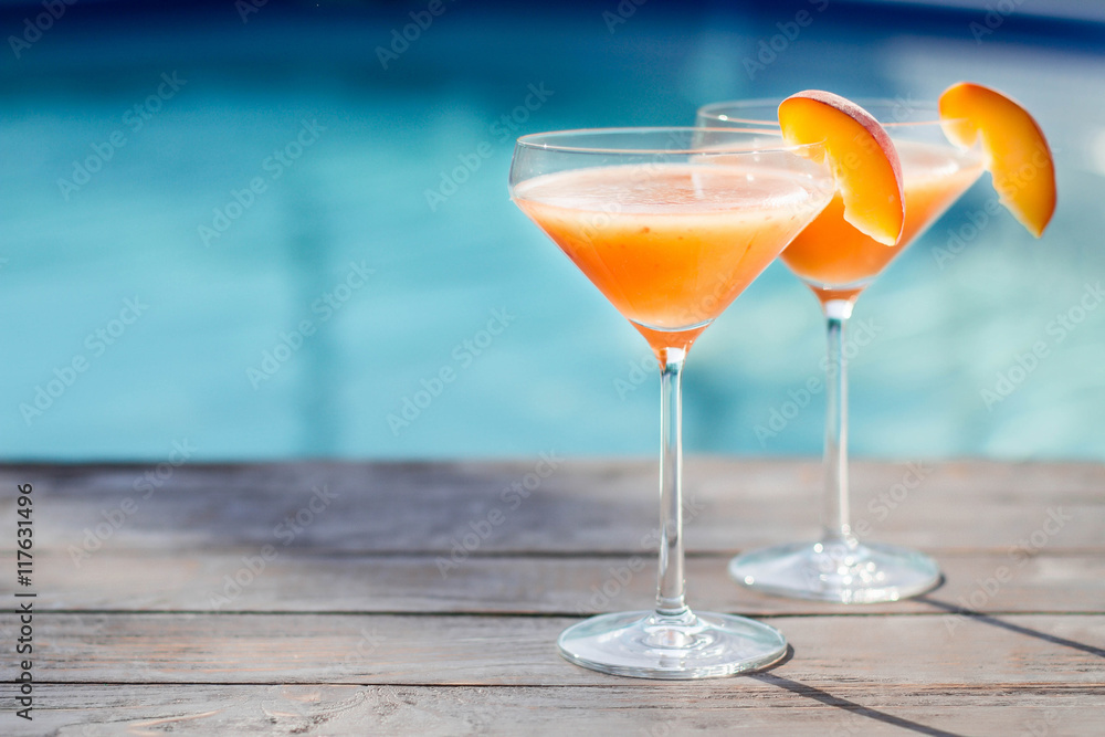 Bellini cocktail with peach isolated near pool
