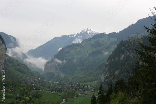 Landscape in the Alps with village and snowcapped mountain tops in the background