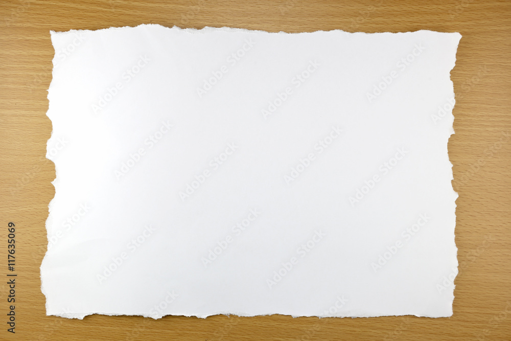 white paper tear on brown wood background.