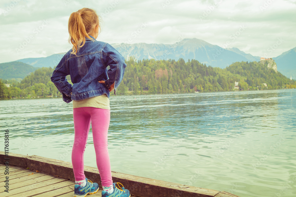 Little girl standing straight on a pier near the lake. Stock Photo ...