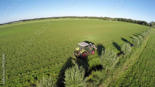 Aerial bird view of tractor mowing grass showing the green landscape tractor cutting the grass in straight lines after this it is dried into hay modern farmer working on the meadow in farmland 4k photo