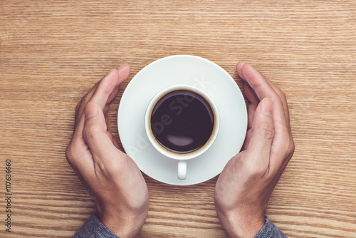 Male hands holding cups of coffee on rustic wooden table backgro