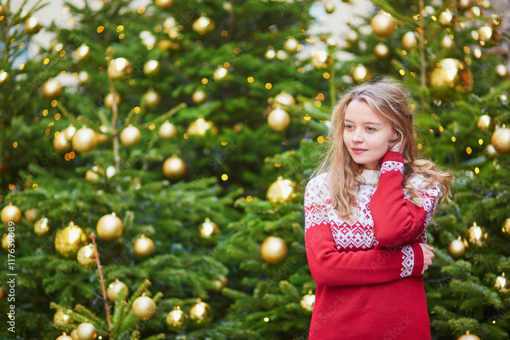 Young woman on a street of Paris decorated for Christmas