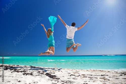 Happy couple jumping on beach photo
