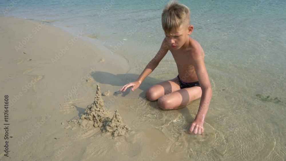 The boy builds a sand castle at the lake. Slow motion The boy builds a sand castle at the lake. Slow motion
