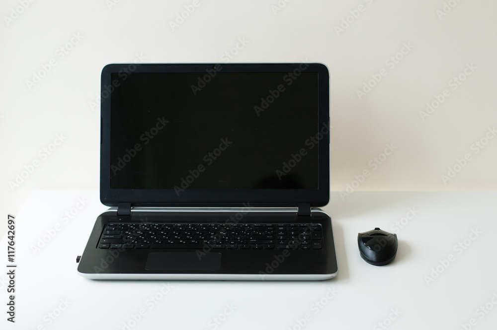 Black partable notebook and mouse. Computer on white table. Office or business concept Black partable notebook and mouse. Computer on white table. Office or business concept