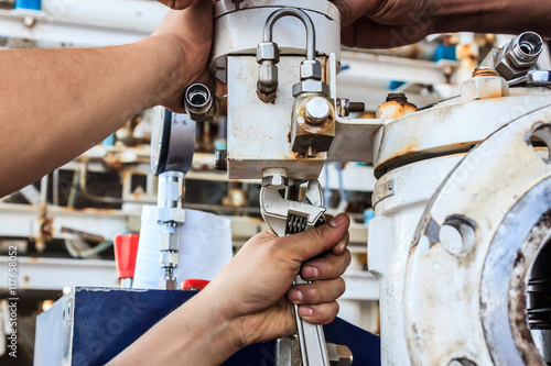 Hand instrument technician adjust tubing pipeline on offshore gas platform.