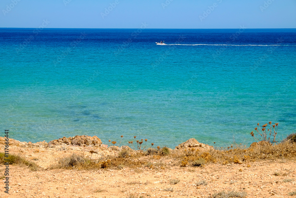 View on the sea with blue water and a mooving white boat.