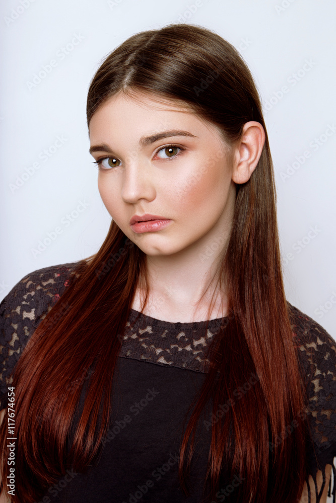 A beautiful 13-years old girl dressed in jeans and T-shirt in studio on white background