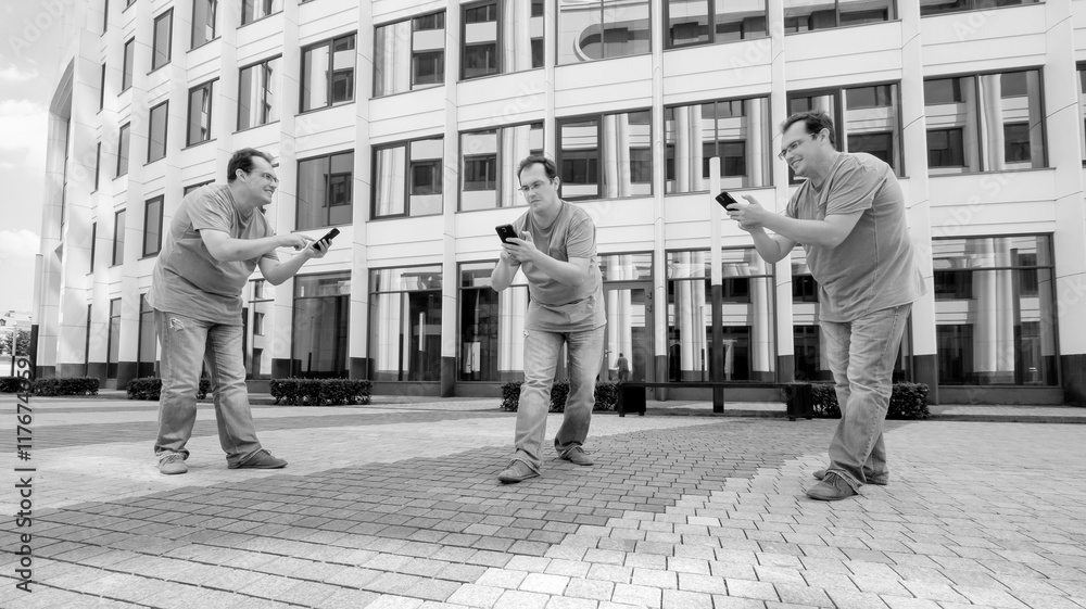 Three men with a mobile phone in front of a white business cente