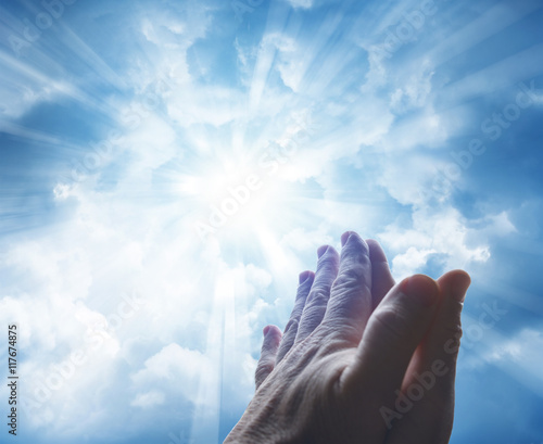 Hands praying in prayer. Bright heavenly sky