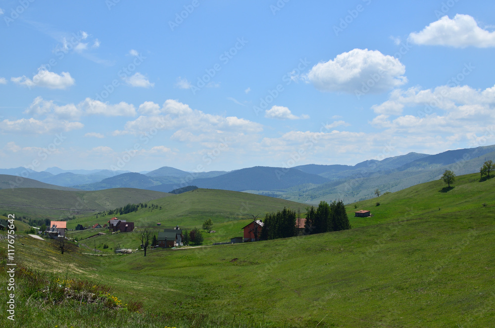 Landscape of Zlatibor Mountain in Serbia with hills, meadows and mountain houses, on sunny spring day