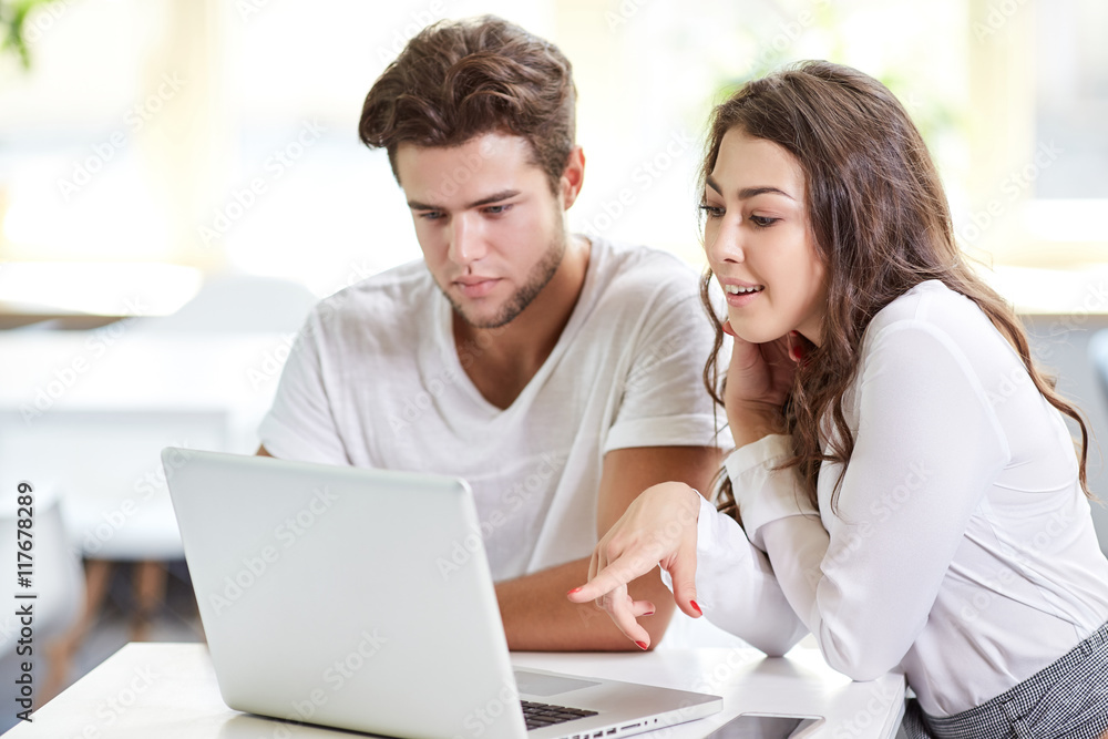 Two young business people in casual wear looking at the laptop. Two young business people in casual wear looking at the laptop.