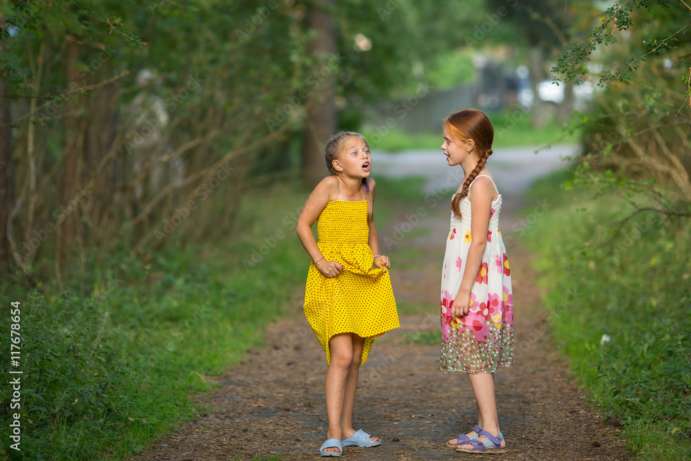 Two little cute girlfriends animatedly talking in the Park. Two little cute girlfriends animatedly talking in the Park.