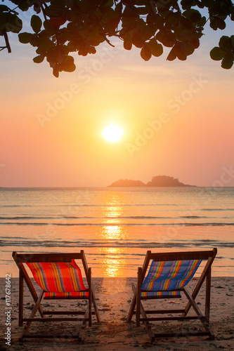 A couple of sun loungers on the beach during sunset.