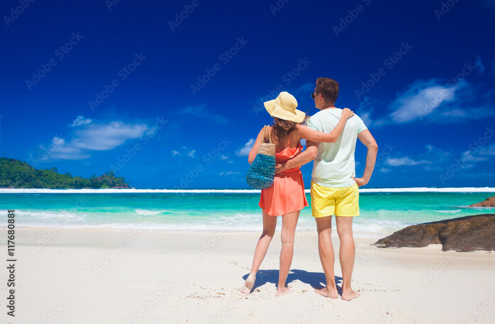 Couple in bright clothes on a tropical Baie Lazare beach at Mahe, Seychelles. Couple in bright clothes on a tropical Baie Lazare beach at Mahe, Seychelles.
