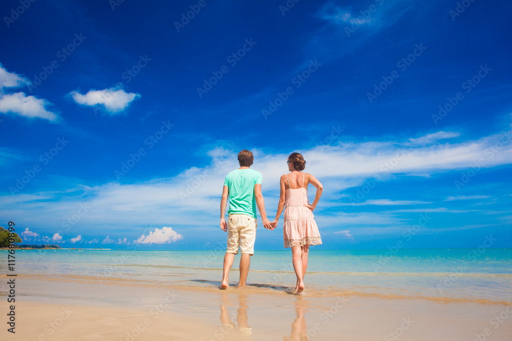 couple in bright clothes walking at tropical beach