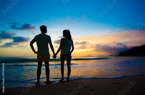 sunset silhouette of young couple in love at beach