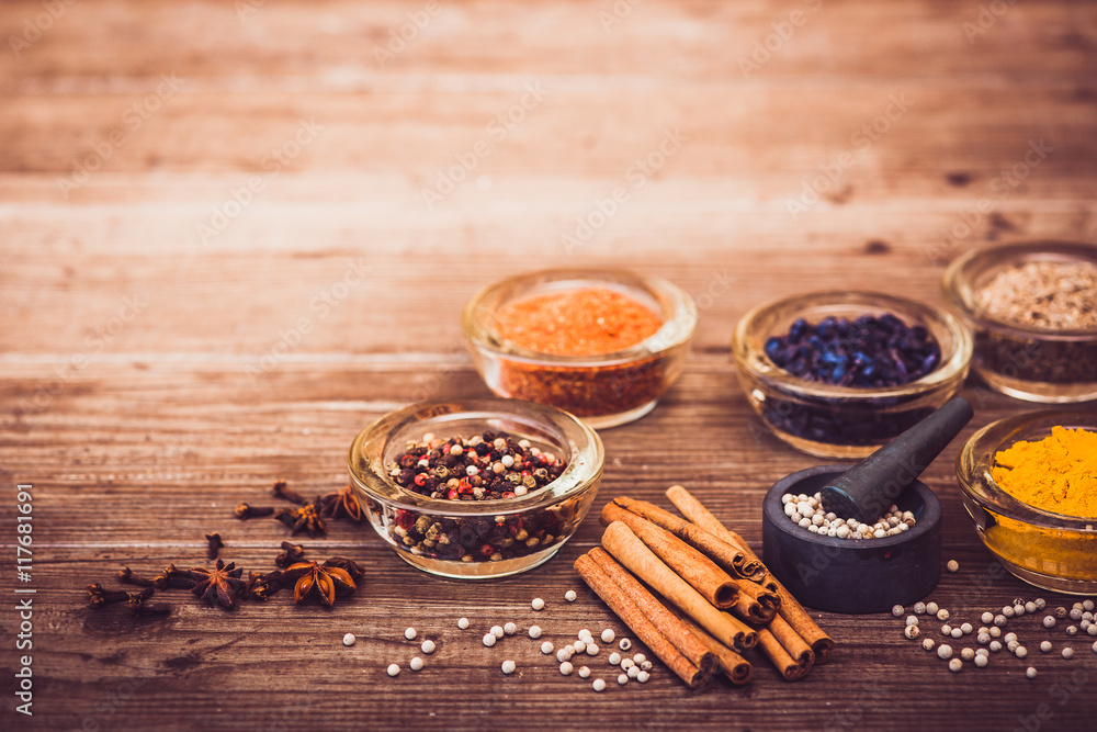 Spices and condiment for cooking: turmeric, pepper, barberry, cinnamon, carnation on the table. Warm toned. Copy space at the top.