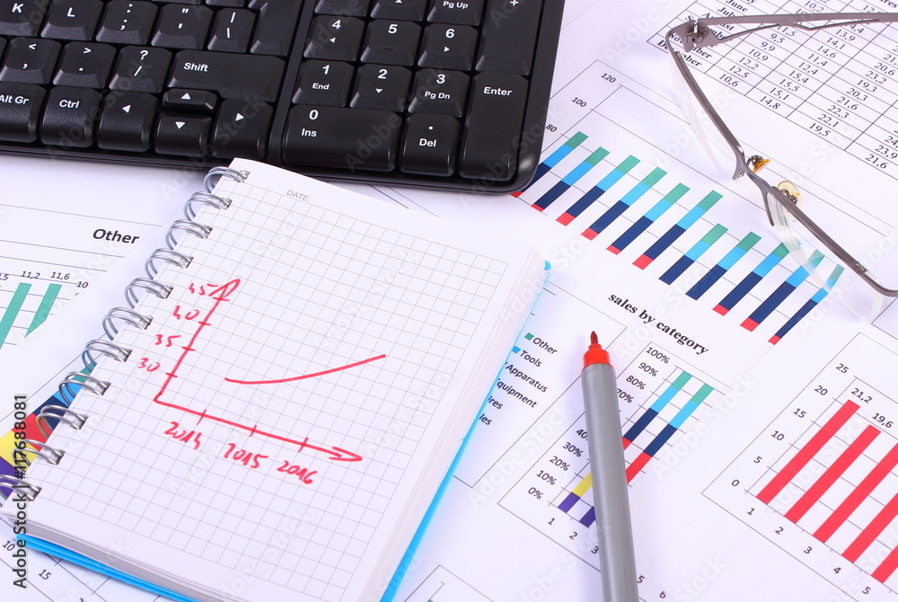 Pen, glasses and computer keyboard on financial graph, business concept Pen, glasses and computer keyboard on financial graph, business concept