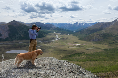 Photography man and his dog admire the mountain scenery