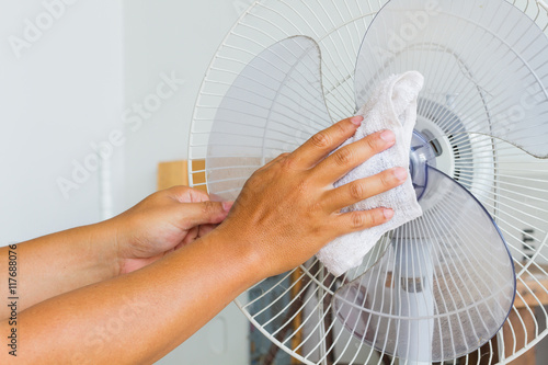 Close up horizontal photo of male hand cleaning dirty electric fan