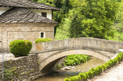 Old stone country house and stone vaulted bridge over small river