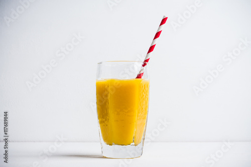 Glass of fresh orange juice on the white wooden background