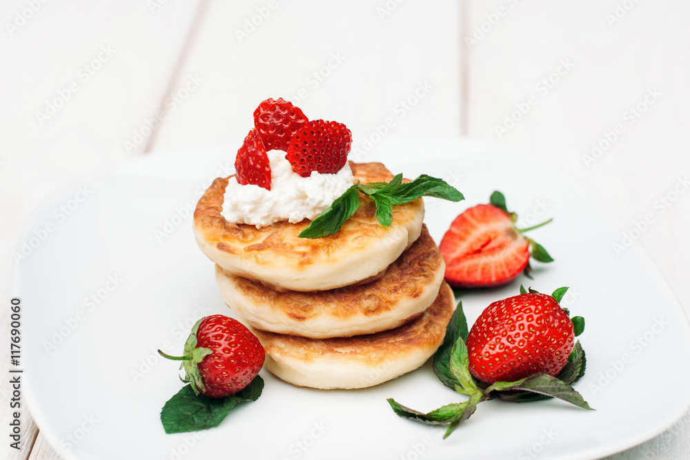 Pancakes with fresh strawberry and cream on white plate. Sweet traditional breakfast for lovers at hotel Pancakes with fresh strawberry and cream on white plate. Sweet traditional breakfast for lovers at hotel