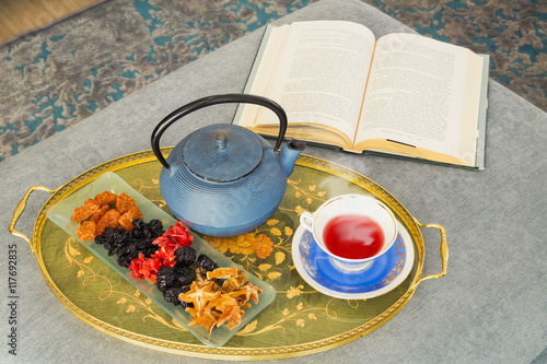 Book, cup of tea. dried fruitsa and teapot photo