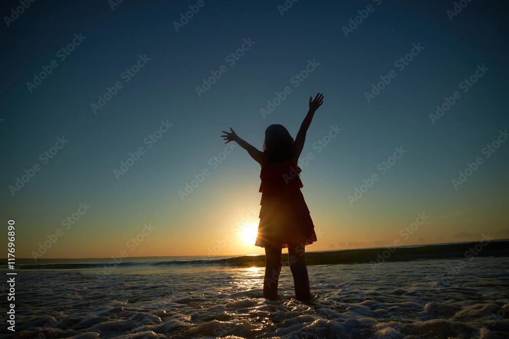 girl playing on the beach at sunset