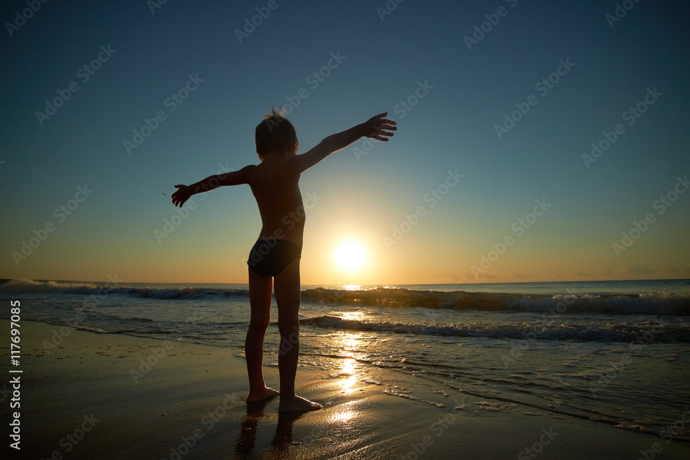 Fototapeta premium boy playing on the beach at sunset