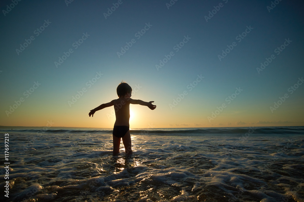 boy playing on the beach at sunset