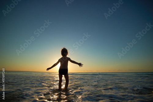 boy playing on the beach at sunset